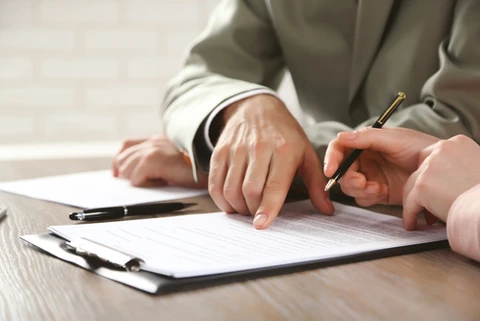 Scène d'affaires en intérieur avec deux personnes en costumes travaillant sur des documents contractuels