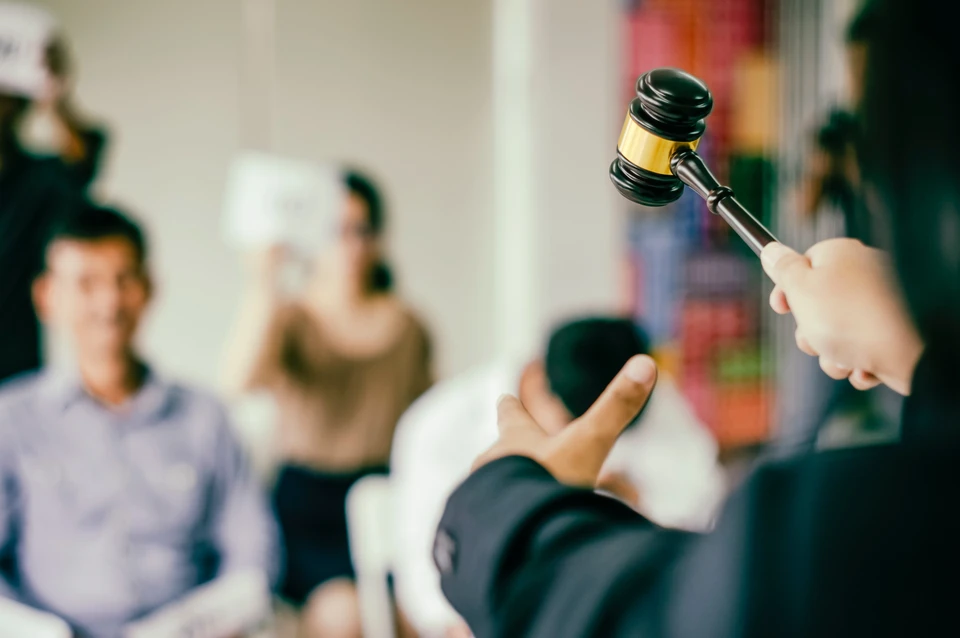 Sc&egrave;ne d'int&eacute;rieur juridique avec personne en robe d'avocat noire &agrave; bandes rouges tenant un livre reli&eacute; rouge