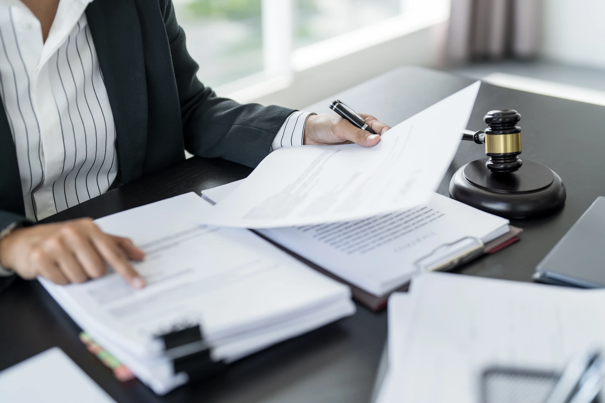 Réunion d'affaires autour d'une table blanche avec trois personnes en costumes sombres analysant des documents contractuels et graphiques statistiques